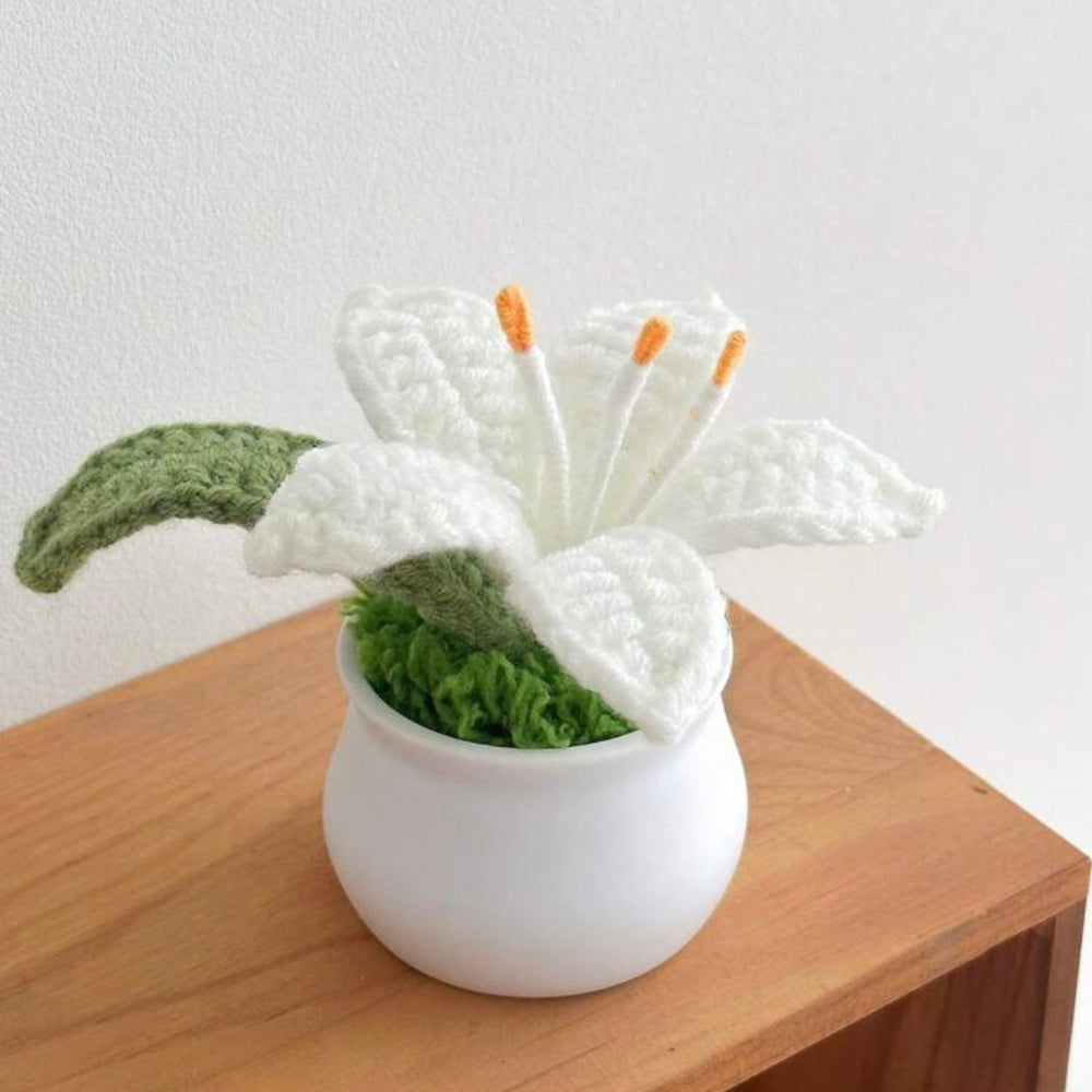 Knitted white flower with green base on a wooden surface