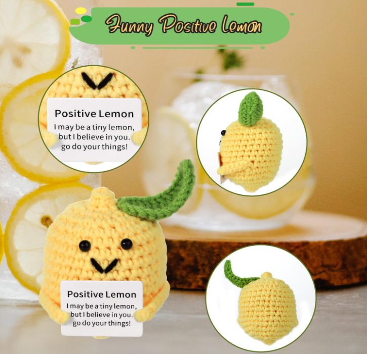Crocheted lemon toy with a smiling face and text, surrounded by lemon slices and a glass of water.