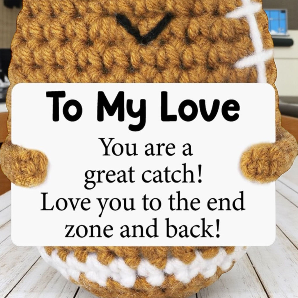 Crocheted football with a sign reading 'To My Love' on a wooden surface