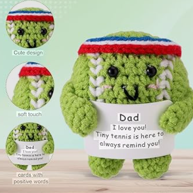 Green plush toy with a red and blue hat, holding a card that says 'Dad, I love you! Tiny tennis is here to always remind you.' on a light green background.