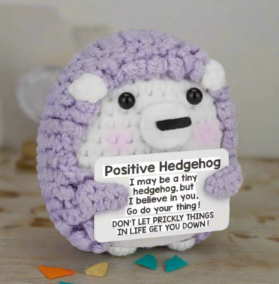 Purple hedgehog plush toy with a motivational message on a wooden surface