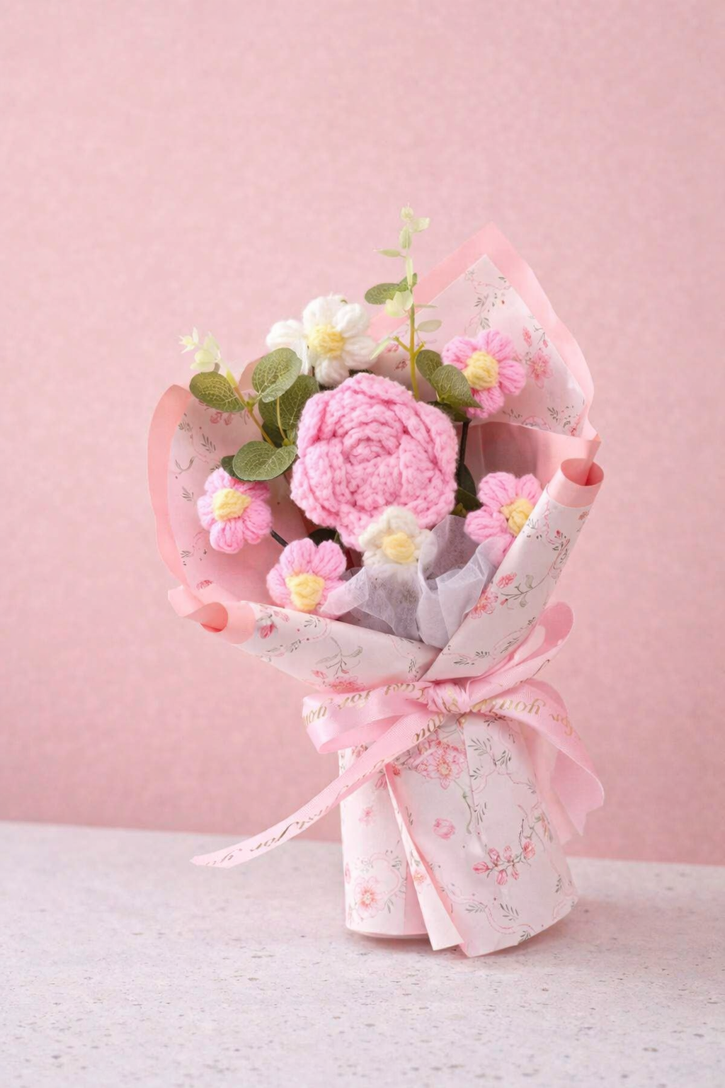 Bouquet of pink flowers in a transparent wrap with floral ribbon on a pink background