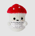 Crocheted mushroom with a red cap and white body, featuring text on a light gray background.