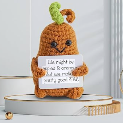 Crocheted pear character holding a sign with humorous text on a light background