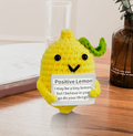 Amigurumi lemon plush toy with a motivational card on a wooden surface