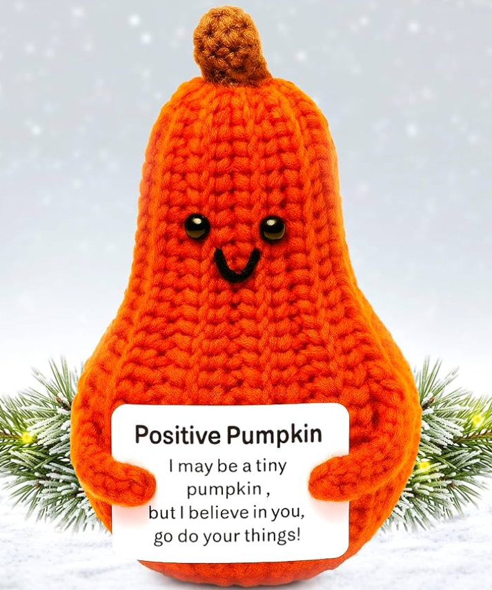 Crocheted pumpkin with a smiling face and a motivational message on a light background