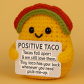Crocheted taco plushie with a sign on a yellow background