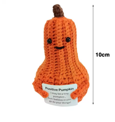 Crocheted pumpkin toy with a label and measurement indicator on a white background