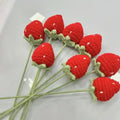 Crocheted red strawberries with green stems on a white background