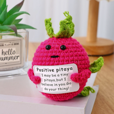 Pink toy pitaya with a motivational message on a white surface