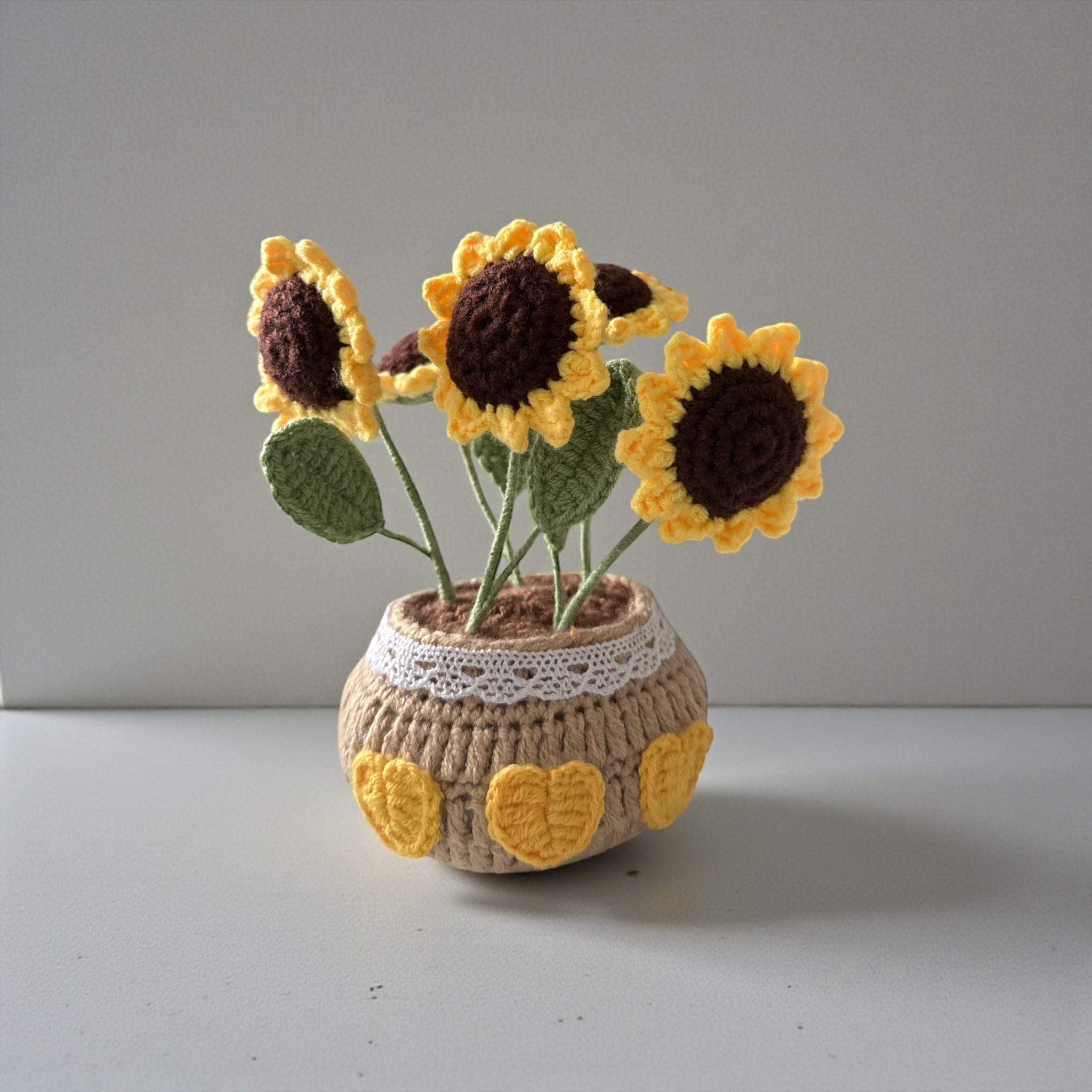 Crocheted sunflowers in a pot on a plain background