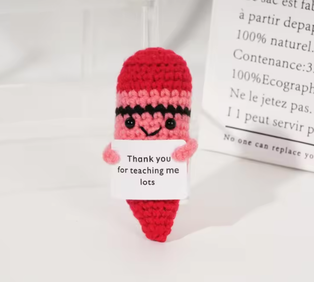 Crocheted character with a red hat and pink body on a white background